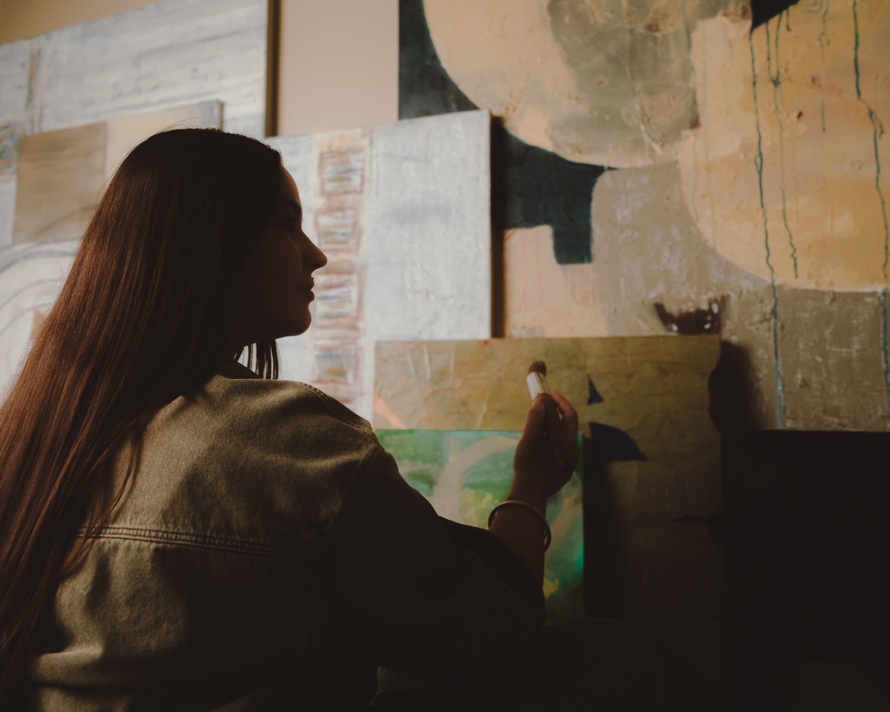 Person painting on a canvas with abstract art in the background